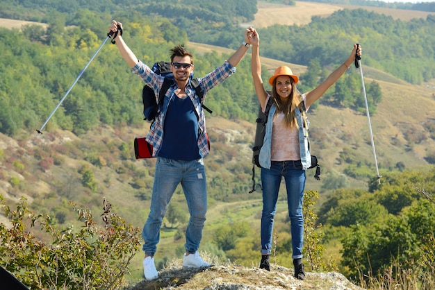 Une fille et un gars ont gravi la montagne et levé la main.