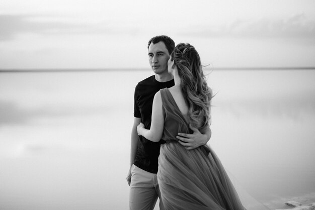 Fille et un gars sur la rive d'un lac salé rose au coucher du soleil