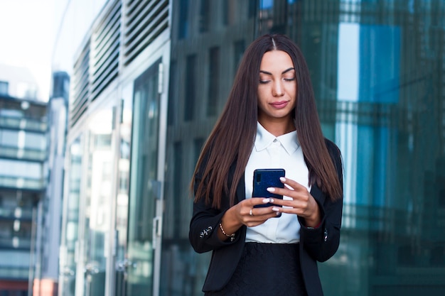 Fille glamour élégante ou jeune femme d'affaires en tapant ou en envoyant un message ou un SMS sur son téléphone portable. Belle femme regardant un smartphone, discutant dans les médias sociaux.