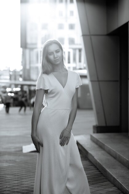 Une fille glamour porte une tenue tendance marchant sur l'avenue dans la douce lumière du soleil du soir