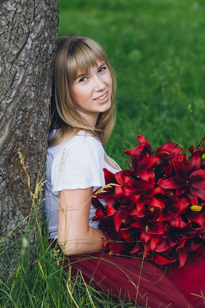 Fille avec un grand bouquet de lys violets