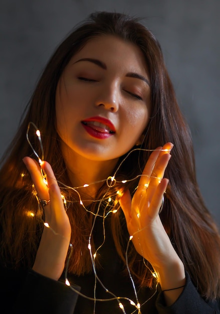 Une fille avec une guirlande de Noël dans ses mains.