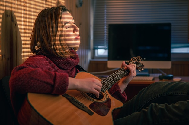 Fille avec une guitare au soleil à travers les stores