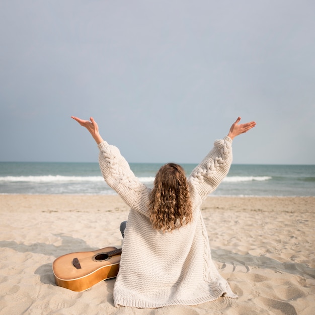 Fille et guitare sur la plage depuis le dos