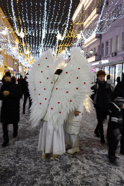 Fille habillée comme un ange blanc dans la rue de la ville nocturne