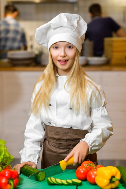 Photo fille habillée en cuisinier à la cuisine