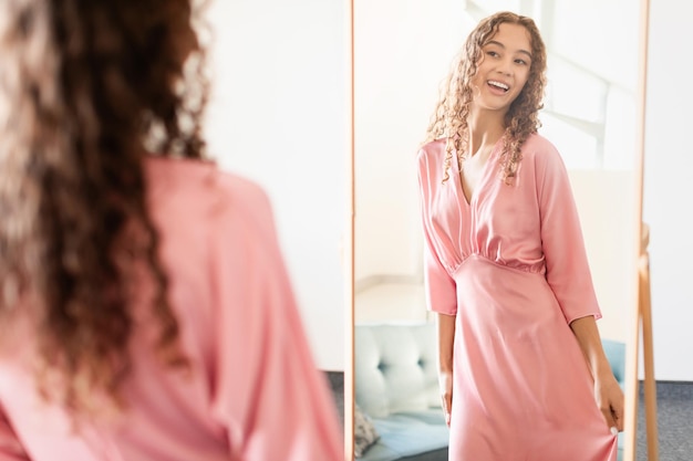 Photo fille habillée d'une tenue élégante devant le miroir à l'intérieur