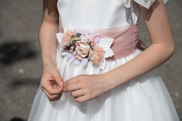 Une fille habillée très élégamment pour sa première communion se tient la main