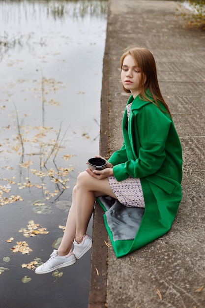 Fille en habit vert se promène au bord du lac en automne