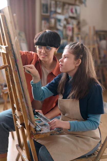 Une fille handicapée apprécie le cours d'art et la peinture sur chevalet.