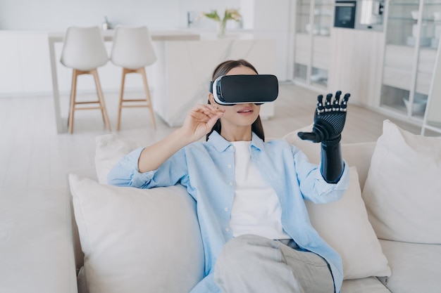 Fille handicapée avec bras cyber dans des lunettes vr Une personne handicapée obtient une réadaptation à la maison