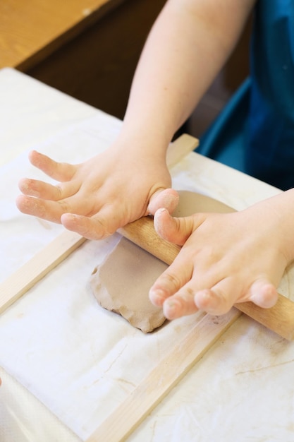 Une fille handicapée déroule de l'argile pour modeler