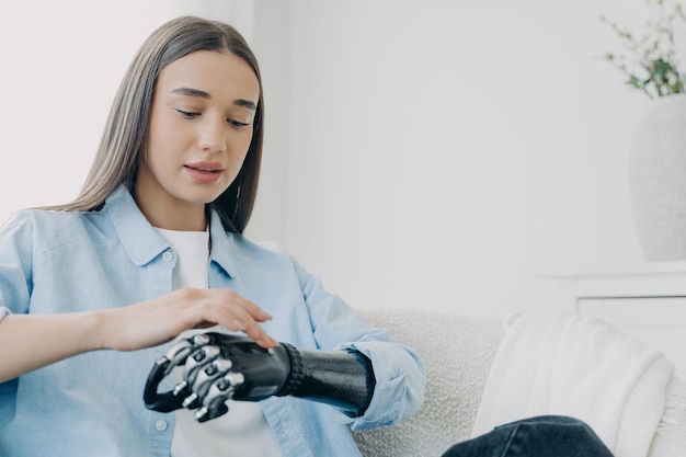 Une fille handicapée explore son bras bionique et appuie sur des boutons Technologie futuriste