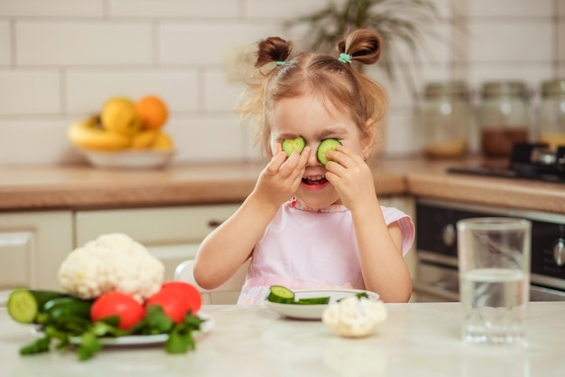 Photo une fille heureuse de 23 ans dans la cuisine à la maison ou à la maternelle mange des légumes délicieux et sains pour le déjeuner