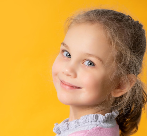 Fille heureuse à l'aide de tablette isolé sur fond orange