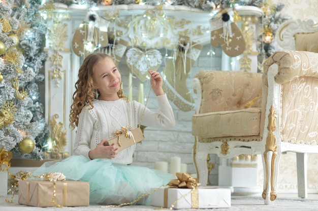 Une fille heureuse assise avec des cadeaux à Noël.