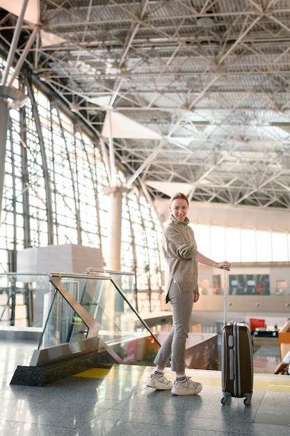 Fille heureuse attend le départ à l'aéroport