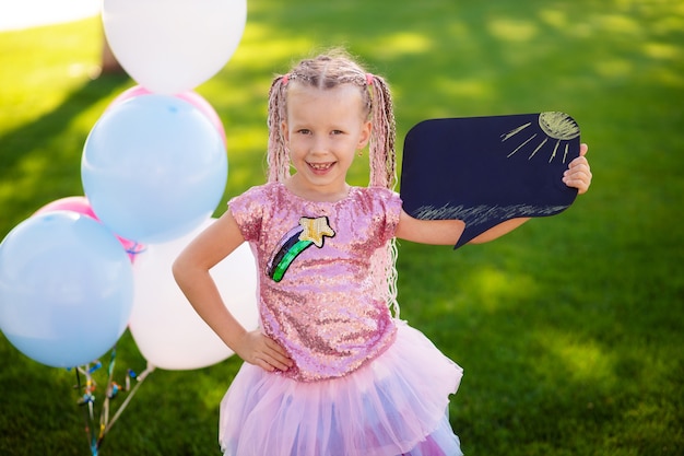 Fille heureuse avec des ballons dans la nature dans le parc