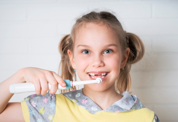 Fille heureuse avec brosse à dents électrique se brosser les dents et souriant