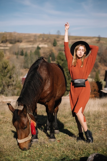 Fille heureuse avec un chapeau noir avec un cheval