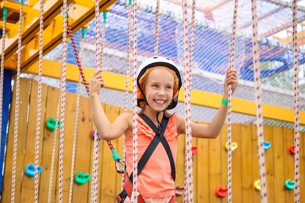 Fille heureuse sur le chemin de la corde dans le centre d'amusement pour les enfants