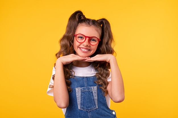 Fille heureuse en combinaison en denim et lunettes