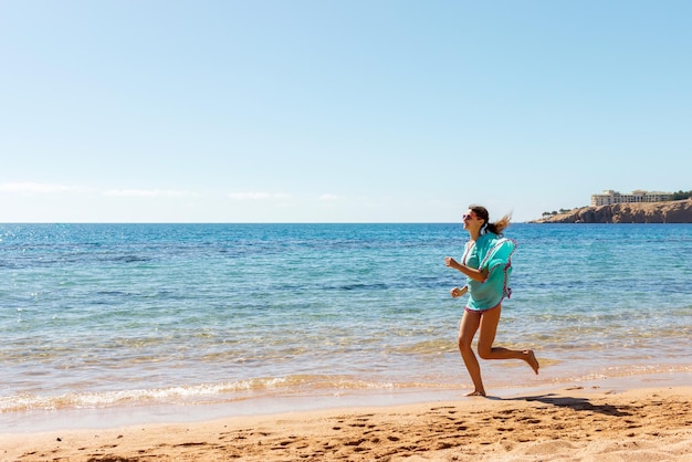 Fille heureuse courir le long de la côte de la mer