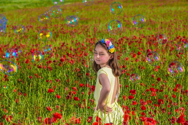 Fille heureuse dans le champ fleuri avec des bulles de savon