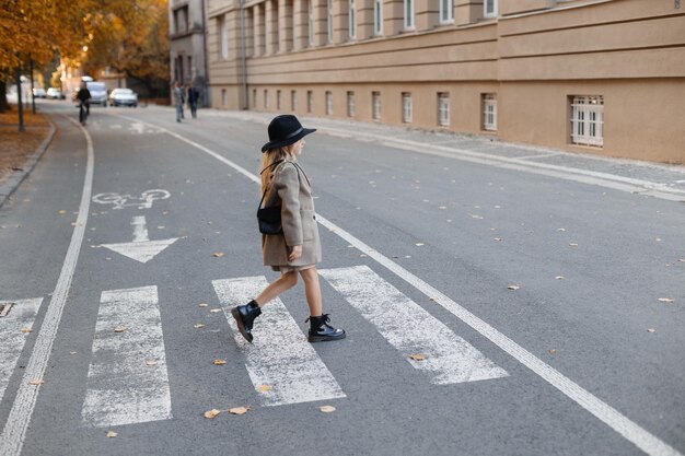 Une fille heureuse dans un chapeau marche et se pose comme modèle sur le front de mer près du piéton