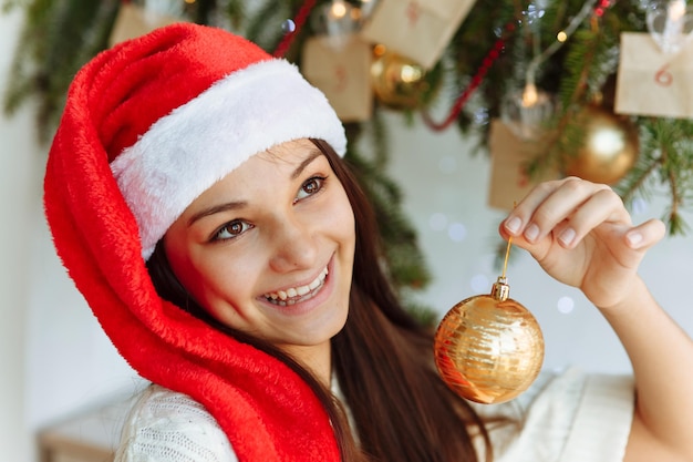 fille heureuse dans un chapeau de Noël avec un jouet d'arbre de Noël dans sa main en gros plan