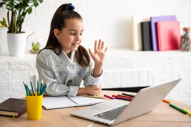 La fille heureuse dans les écouteurs avec un ordinateur portable assis à la table