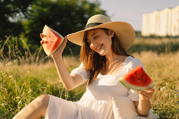 Une fille heureuse dans un parc extérieur avec des fruits de pastèque rafraîchissante une femme mange un morceau de pastèque