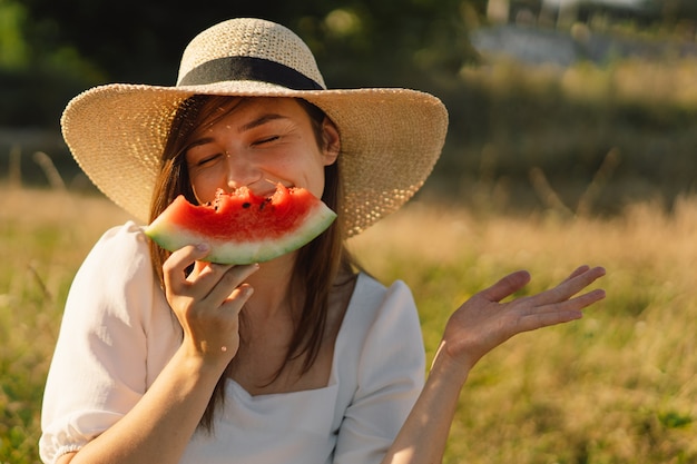 Une fille heureuse dans un parc extérieur avec des fruits de pastèque rafraîchissante une femme mange un morceau de pastèque