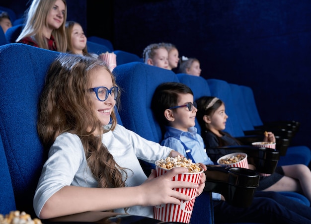 Fille heureuse dans des verres, manger du pop-corn et rire au cinéma