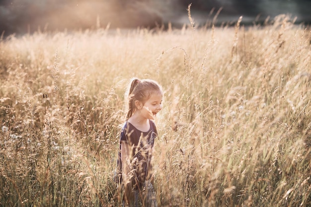 Une fille heureuse debout au milieu des plantes sur le champ