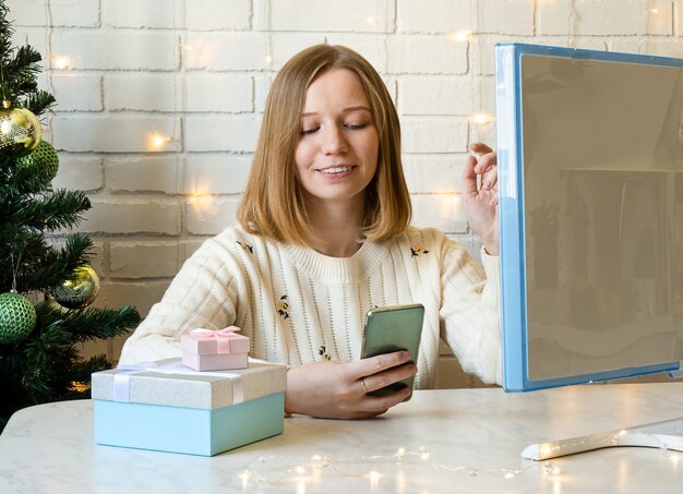 Une fille heureuse discute avec des amis sur un smartphone. concept de Noël en ligne.