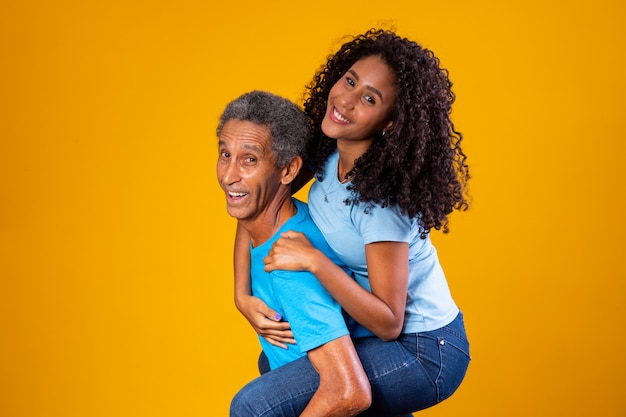 Fille heureuse sur le dos du père sur fond jaune.