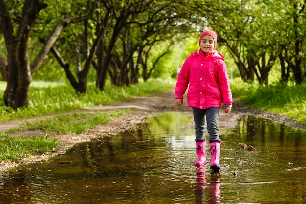 fille heureuse d'enfant courant et sautant dans les flaques d'eau après la pluie