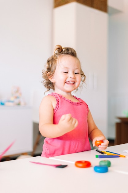 La fille heureuse d'enfant dessine avec des crayons colorés