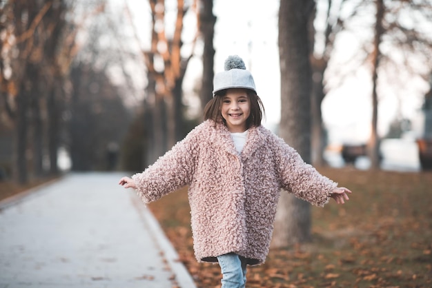 Fille heureuse d'enfant marchant dans le plan rapproché de parc de ville