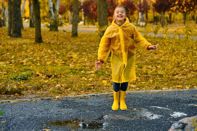 Fille heureuse d'enfant avec un parapluie et des bottes en caoutchouc