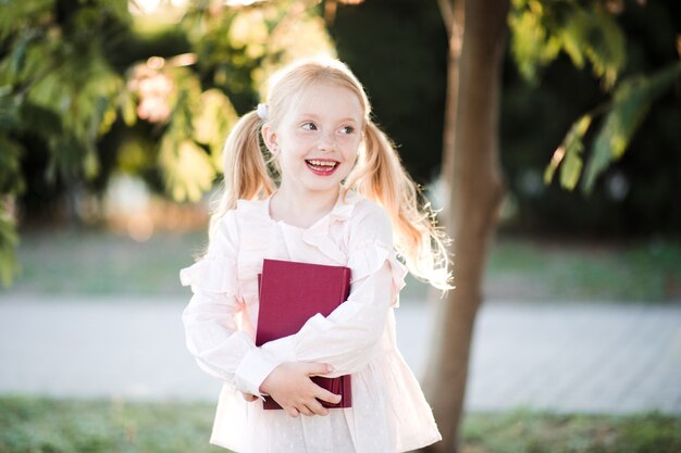 Fille heureuse d'enfant tenant des livres dehors