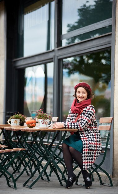 Fille heureuse est assise dans un café dans la rue de Budapest