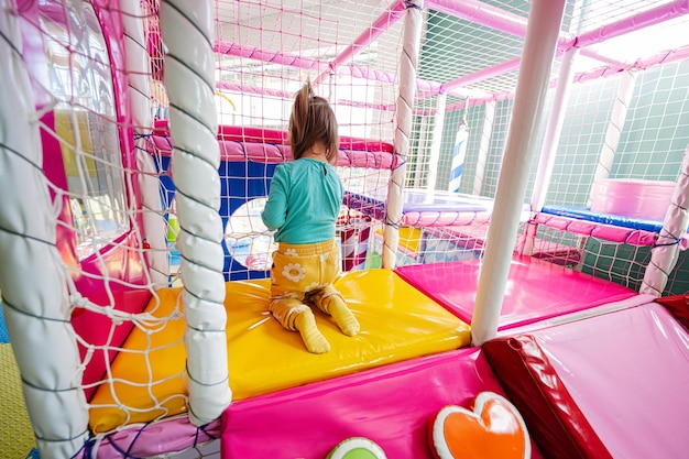 Fille heureuse jouant au terrain de jeu intérieur du centre de jeux Boules de couleur dans la piscine à balles