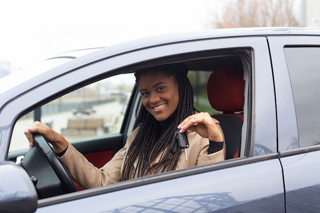 La fille heureuse a loué une voiture, afro-américaine