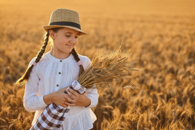 Fille heureuse marchant dans le blé doré, profitant de la vie sur le terrain.