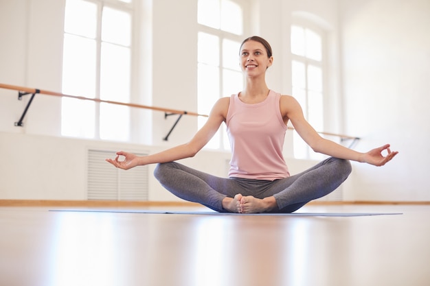 Fille heureuse méditant dans une salle vide