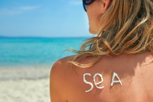 Fille heureuse sur la mer avec une photo du soleil sur le dos