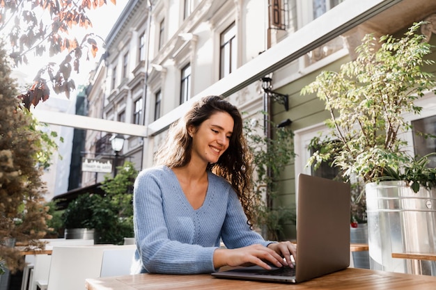 Une fille heureuse avec un ordinateur portable discute avec ses amis et sa famille en plein air dans un café Une femme d'affaires confiante discute à l'aide d'un ordinateur portable avec des collègues via une connexion vidéo et discute de nouvelles idées