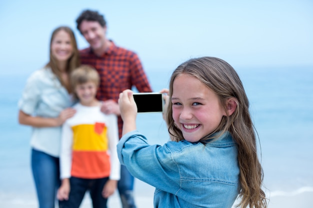 Fille heureuse photographier la famille avec téléphone portable